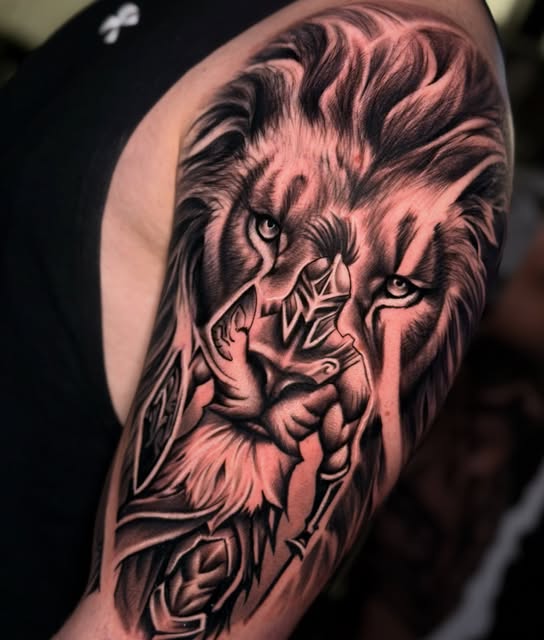 Leão em realismo preto e cinza tatuado no braço